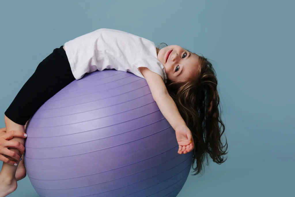 Dziewczynka leżąca na plecach na piłce fitnessowej