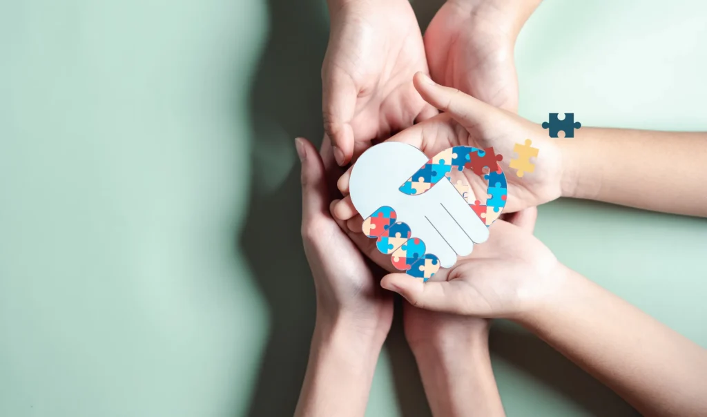 Dłonie rodziny trzymające serce ułożone z puzzli - symbol świadomości spektrum autyzmu