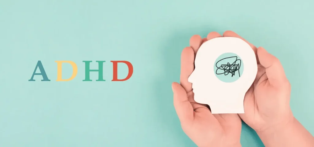Napis adhd na zielonym tle obok rąk dziecka